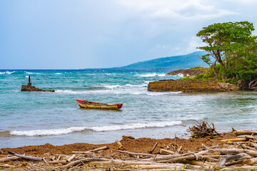 Seascape coastline setting on tropical Caribbean island. Old wooden fishing boat floating in shallow water near white sand seashore on coastal beach with debris/ driftwood/ drift wood/ bamboo logs. © Debbie Ann Powell