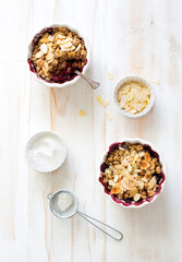 Crumble with berries, apples, and almond in white bowl close up