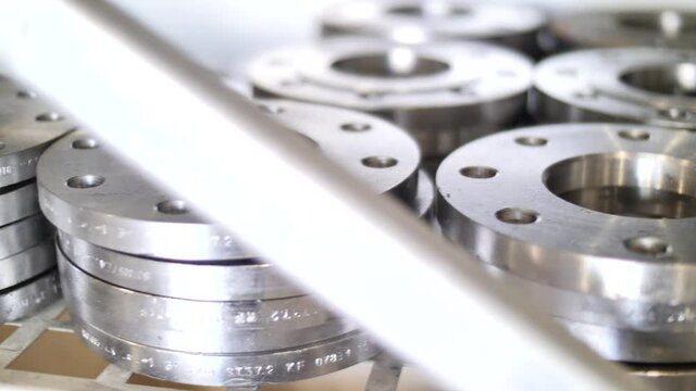 Shiny new stainless steel flanges piled on warehouse, market shelf, close up