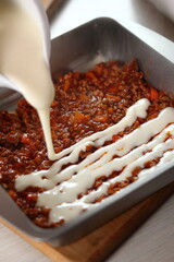 Pouring bechamel sauce onto ground meat layer. Making Lasagna Bolognese Series.