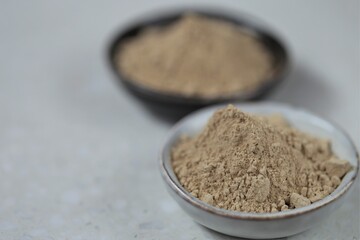 Guarana powder in ceramic black and gray cups on a light marble background.Useful product. Healthy eating.Natural energetic.Super food