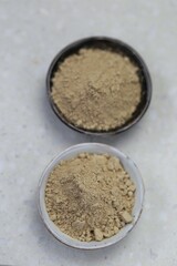 Guarana powder in ceramic black and gray cups on a light marble background.Useful product. Healthy eating.Natural energetic.