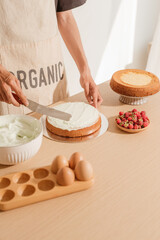 Man putting cream on sponge cake. Making home-made cake process