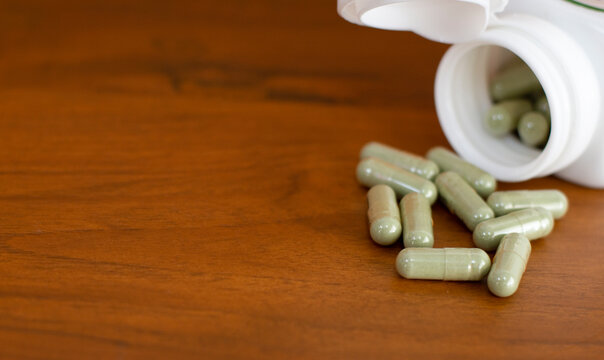 Herb capsule,Herble,Medicine and a bottle on wooden background.