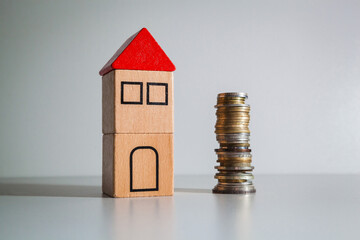 A wooden toy house with a red roof and a stack of coins.