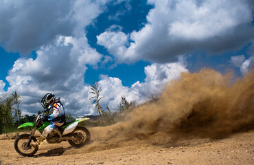 Motocross rider lifting a dirt cloud on the air with rear tire.