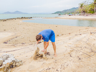 Man in gloves pick up plastic bags that pollute sea. Problem of spilled rubbish trash garbage on...