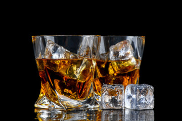 Glass of whiskey with cube ice on black background