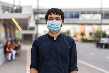 Fototapeta na wymiar young man wearing medical mask for prevention from coronavirus (Covid-19) pandemic on street in the city. new normal concepts