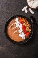 Healthy breakfast bowl. Chocolate banana smoothie bowl with coconut flakes, granola, strawberry. Top view, flat lay, overhead
