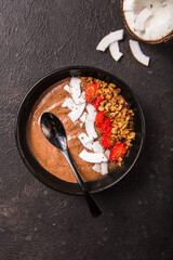 Healthy breakfast bowl. Chocolate banana smoothie bowl with coconut flakes, granola, strawberry. Top view, flat lay, overhead. Bowl of blackberry banana smoothie with coconut flakes