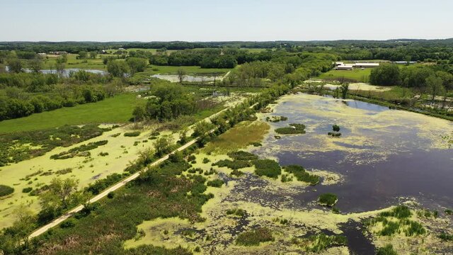 Aerial view of open water marsh and recreational trail through it. Midwestern landscape, wilderness from above. Daytime, summer