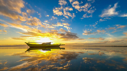 yellow fishing boat on a beautiful sunset with mirrored water