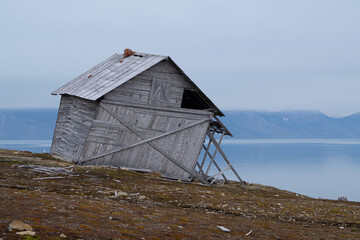 Crooked wooden cabin which is standing alone and abandoned in the tundra on Spitsbergen
