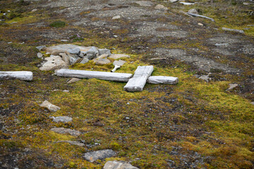Wooden cross lying on the ground at an old and abandoned grave on Spitsbergen