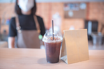 Barista  in apron and face mask standing  behind counter bar ready to give Coffee Service at the modern coffee shop, Modern cafe business, Social distancing concept. 