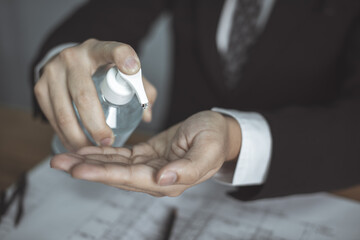 businessman washing hands with an alcohol gel in a pump-like bottle to prevent the spread of the Covid-19 virus.