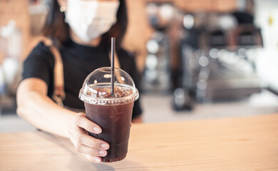 Barista  in apron and face mask standing  behind counter bar ready to give Coffee Service at the modern coffee shop, Modern cafe business, Social distancing concept. 