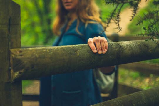 Woman with hand on wooden gate in forest