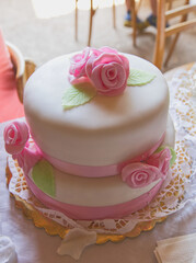 Gorgeous cute white-and-pink wedding cake with marzipan roses, decorated with pink ribbon, two-story wedding cake