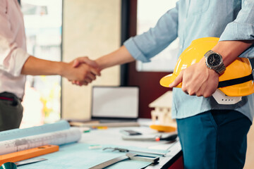 architect hold safety helmet. Blur architect, Engineer and businessman handshake after meeting together Background.