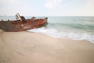 Old rusty fishing boats on the sandy beach near the sea.