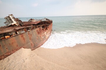 Old rusty fishing boats on the sandy beach near the sea.