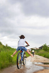 Fototapeta premium Child, boy, riding bike in muddy puddle, summer time