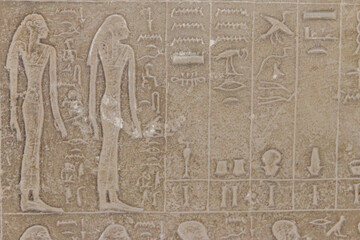 Ancient egyptian paintings and hieroglyphs carved on the stone wall