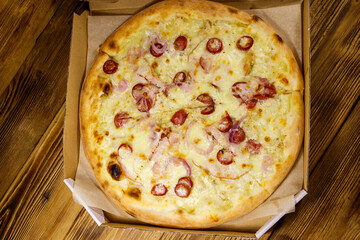 Delicious fresh pizza in cardboard box on a wooden table. Top view. Concept for home delivery of food, fast food, delivery of pizza