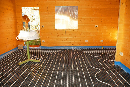 A Hydronic Closed Loop Underfloor Heating System Laid Out On A Molded Insulated Panel In EPS With A Spooling Table Inside A Partially Constructed Wooden House
