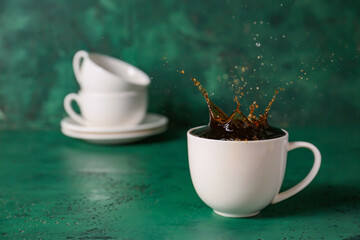 Cup of hot coffee with splash on table