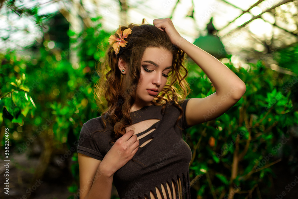 Wall mural young woman with curly hair walking between succulent plants in beautiful tropical botanical garden