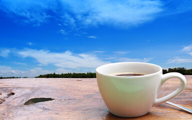 Coffee cup put on old wood table on green tree and blue sky background