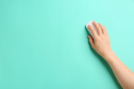 Female hand with modern computer mouse on color background