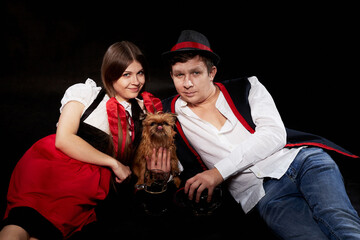 Happy Oktoberfest couple in national ethnic dress with mug of beer, small shaggy dog resting on...