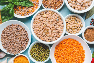 Bowls with lentils and spices on color background