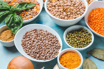 Bowls with lentils and spices on color background