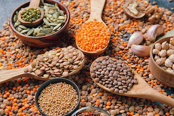 Different raw legumes with spices on dark background
