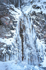 Frozen waterfall in winter. Icicles on the rock.