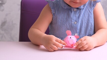 Obraz na płótnie Canvas little girl, together with her mother, makes a soft toy pink pig. Everyday moms, craft with children.