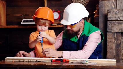 Father teaching son. Father and toddler son carved of wood in carpentry workshop. Sraftsman family. Father and his son working together in a wooden workshop. Happy family, carpentry woodwork concept.