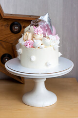 Elegant white cake with isomalt, chocolate, macaroons, meringues, pink and silver elements.