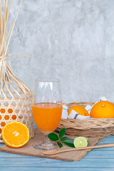 Orange juice in glass with fresh orange in basket on blue wood table