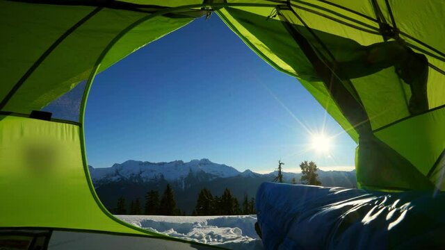 Lockdown shot of sleeping bag in green tent on snow against blue sky during sunrise - Elfin Lakes, British Columbia