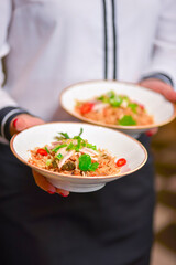 Waiter in white uniform, shirt, serving two plates of delicious fried rice with vegetables.