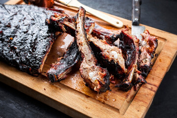 Barbecue veal spare loin ribs St Louis cut with hot honey chili marinade burnt as closeup on an old rustic wooden cutting board