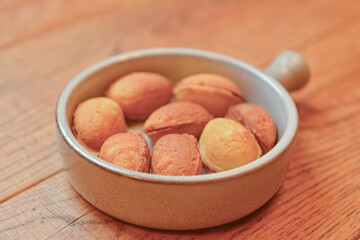 Cookies called nuts with condensed milk served in a white bowl on a wooden table over blurred restaurant background.
