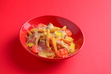 Melting cheddar cheese over the top of french fries covered in spicy sauce with meat and tomatoes. Red background.