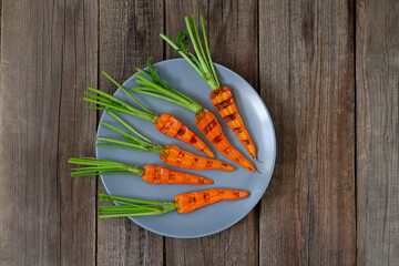 Grilled organic carrots on rustic table from above